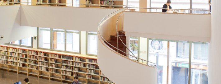 Descripción: Un reportaje fotográfico de una biblioteca con estantes y una escalera de caracol.