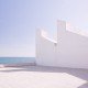 Un edificio blanco junto al océano, bellamente capturado por un talentoso fotógrafo de interiorismo.
