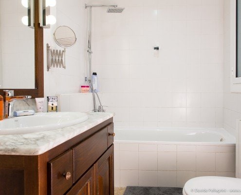 Un baño compuesto por inodoro, lavabo y bañera con el toque artístico de un fotógrafo de arquitectura especializado en fotografía de interiores.