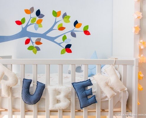 La habitación de un bebé con un árbol en la pared capturada por un talentoso fotógrafo de interiores.