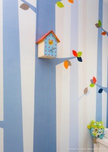 Una habitación infantil con una casita para pájaros y árboles en la pared, capturada por un talentoso fotógrafo de arquitectura especializado en fotografía de interiores y fotografía de arquitectura.