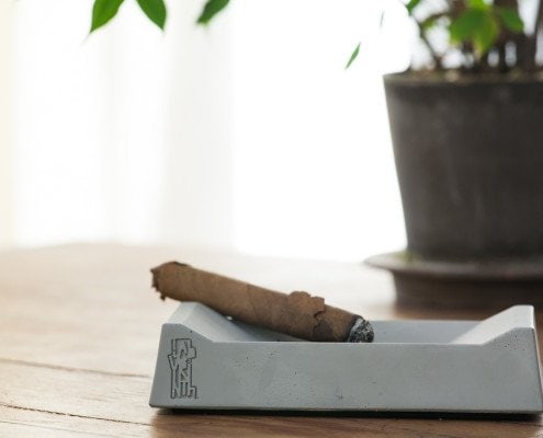 Un cenicero de cigarros sobre una mesa junto a una planta, capturado por un fotógrafo de interiores para un reportaje fotográfico de interiores.