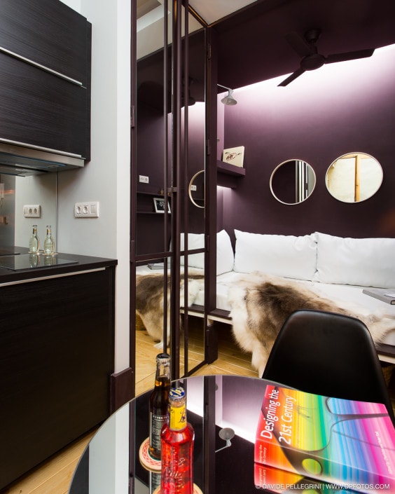Una habitación con una cama, una mesa y un espejo apta para fotografía de arquitectura.