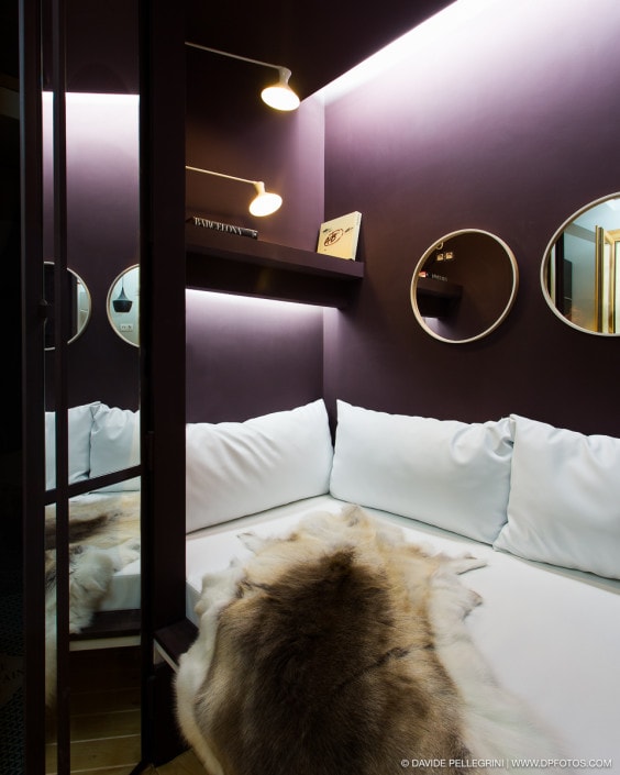 Descripción: Una cama en una habitación con paredes moradas y espejos.
Palabras clave: fotografía de interiores, reportaje fotográfico.