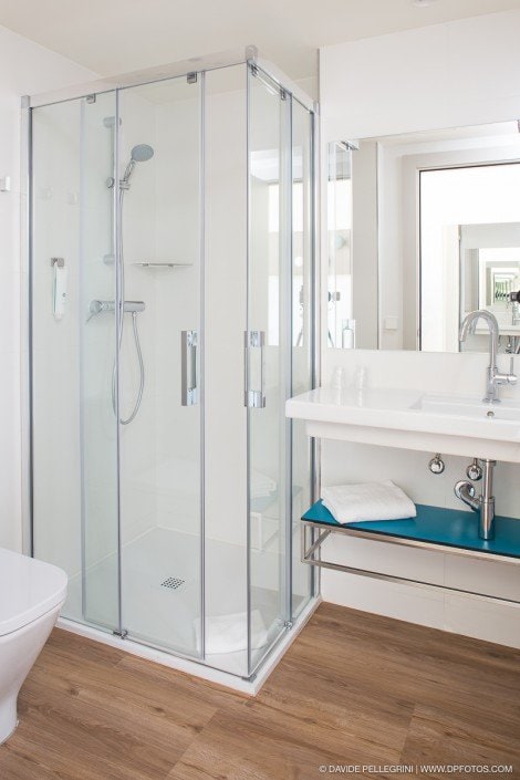 El arquitecto de este baño blanco incorpora de manera experta una cabina de ducha de vidrio, creando una impresionante exhibición de fotografías arquitectónicas.