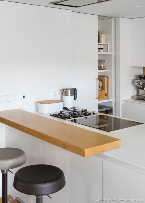 Una cocina moderna con encimeras y taburetes blancos, capturada en una impresionante fotografía.