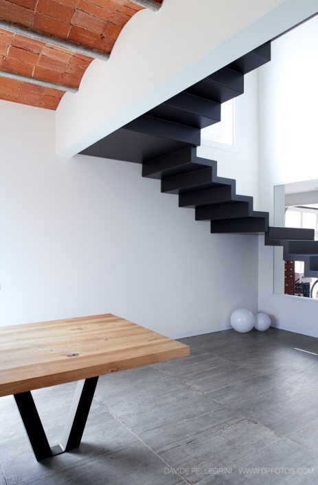 Un reportaje de una vivienda unifamiliar con una escalera y una mesa de madera.