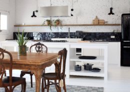 Una cocina blanca con mesa y sillas de madera, ideal para un espacio de apartamento sencillo.