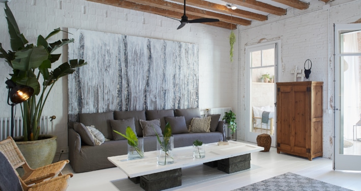 Un salón con paredes blancas y vigas de madera en un diseño de apartamento moderno.