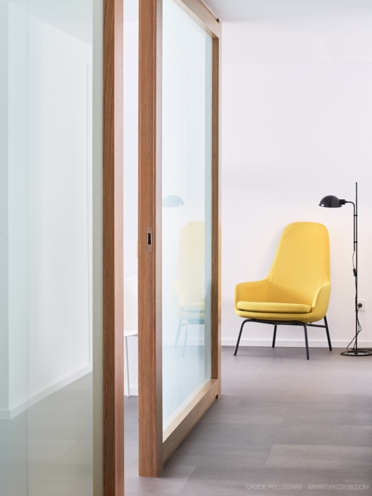 Un consultorio de clínica dental con una silla amarilla y puertas de vidrio.