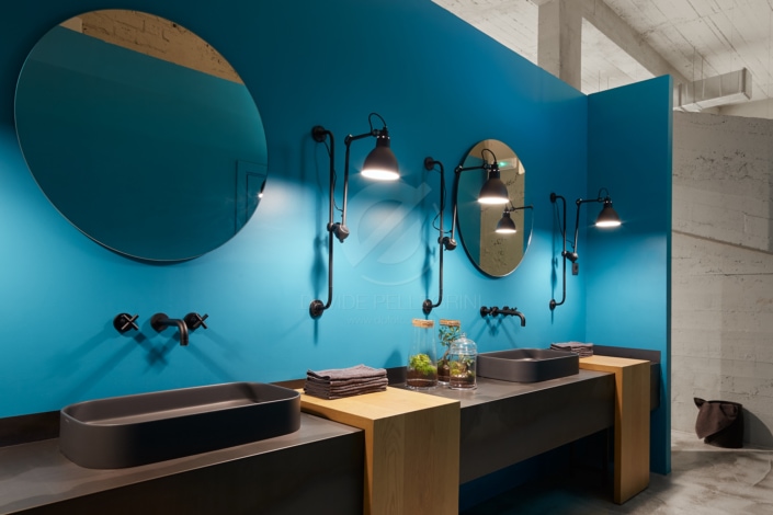 Descripción: Un baño con paredes azules y lavabos negros.