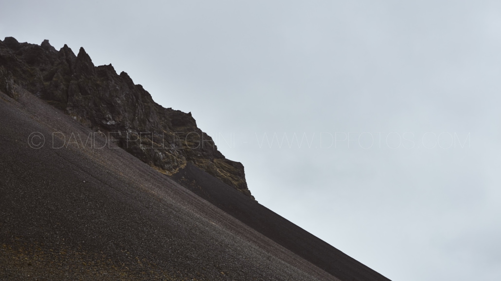 Un fotógrafo captura la majestuosidad de la cumbre de una montaña en medio de un cielo nublado.