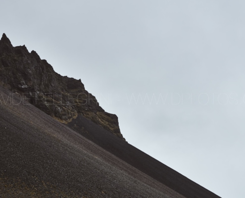 Un fotógrafo captura la majestuosidad de la cumbre de una montaña en medio de un cielo nublado.