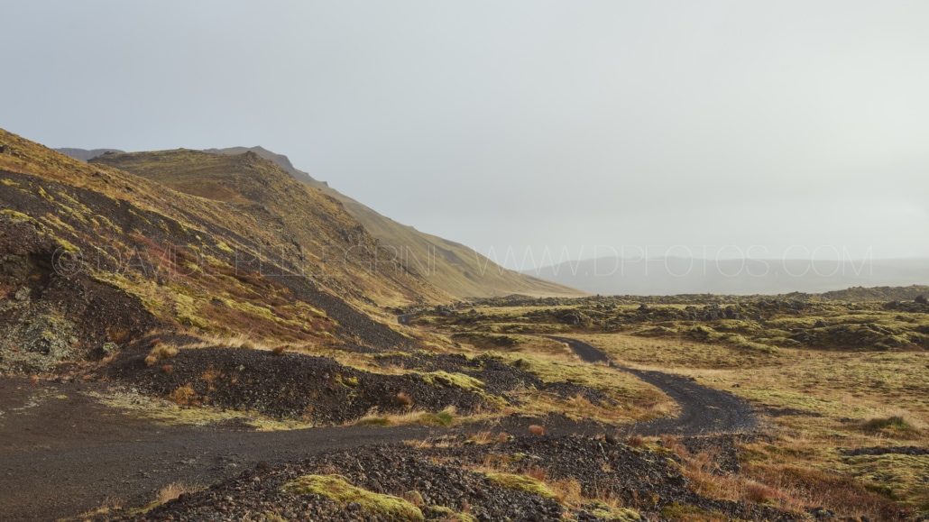 Un camino de tierra que conduce a una montaña en Islandia, capturado por un fotógrafo experimentado especializado en fotografía de paisajes.