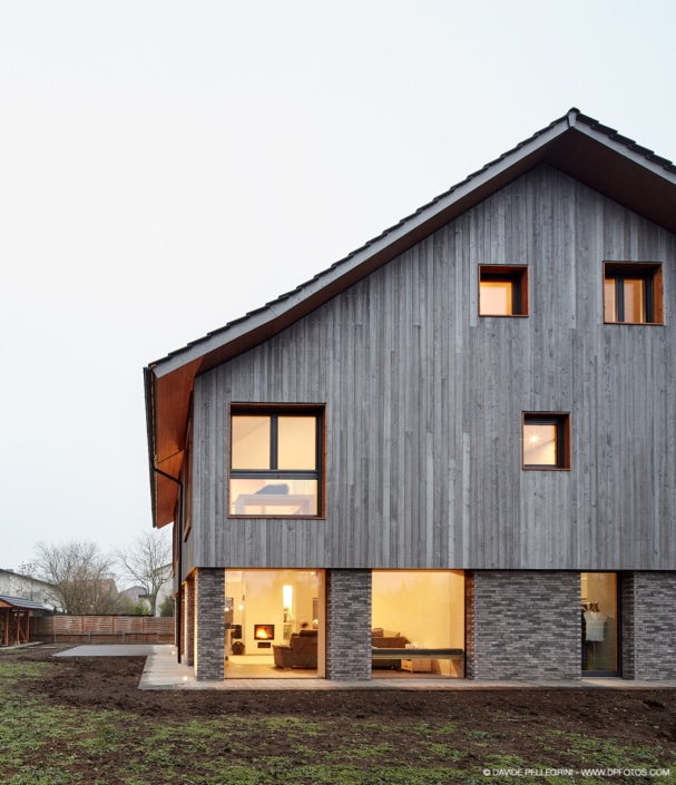 Un reportaje arquitectónico de una casa moderna con revestimiento y ventanas de madera.