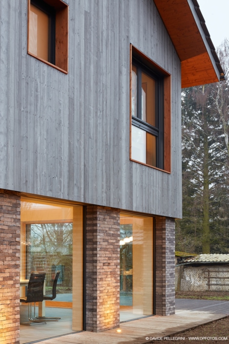Una casa moderna con revestimiento de madera y ventanas de cristal, llamada Casa Gris.