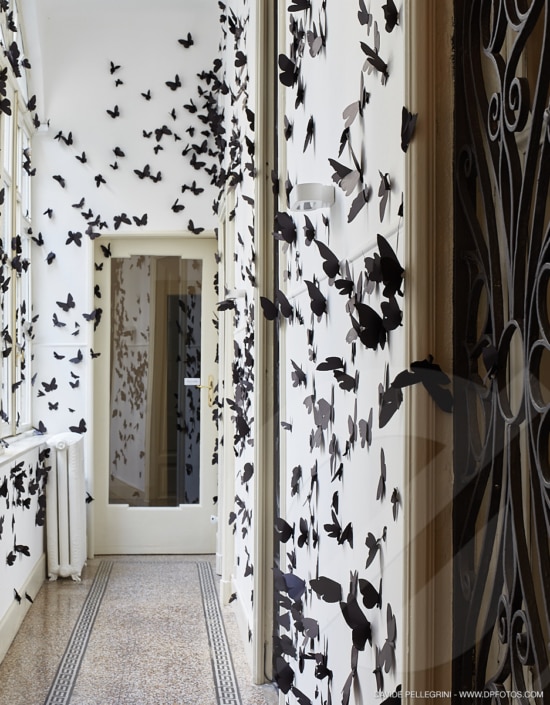 Un pasillo con mariposas negras en las paredes, perfecto para un impresionante reportaje fotográfico de interiorismo.