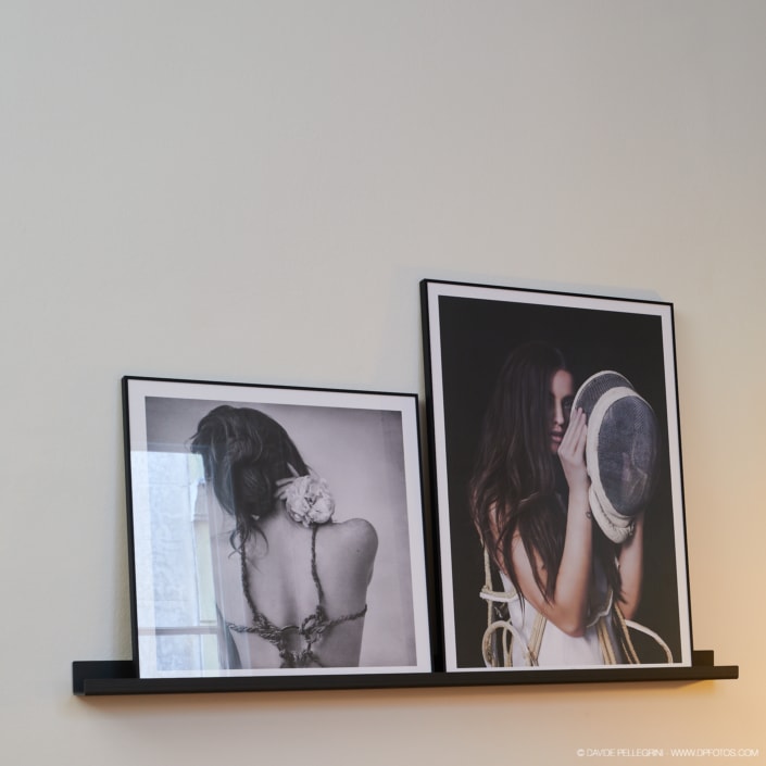 Dos fotografías en blanco y negro en un estante, capturadas como parte de un reportaje fotográfico.