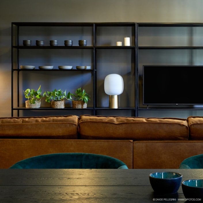 Un salón con un sofá marrón y una televisión. El espacio ha sido renovado para una sesión de fotos que muestra las últimas tendencias en diseño de interiores.