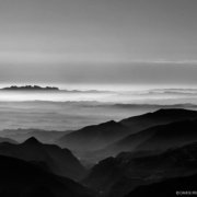 Una fotografía en blanco y negro de una cadena montañosa que captura la majestuosidad de la naturaleza en un estilo de reportaje fotográfico.