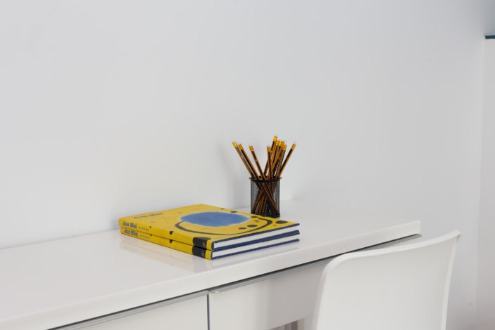 Descripción: Un escritorio blanco con un libro y lápices sobre él.
