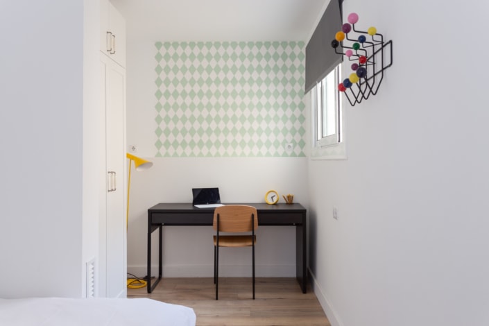 Un dormitorio pequeño con escritorio y silla, perfecto para amantes del interiorismo o interesados en la arquitectura. Capture la esencia de este acogedor espacio con un reportaje fotográfico.