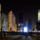 Un grupo de personas paradas en medio de una ciudad por la noche, capturadas en una sesión de fotos arquitectónicas.