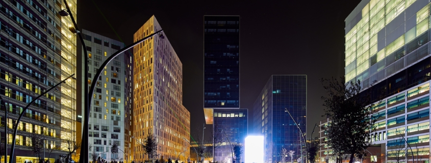 Un grupo de personas paradas en medio de una ciudad por la noche, capturadas en una sesión de fotos arquitectónicas.