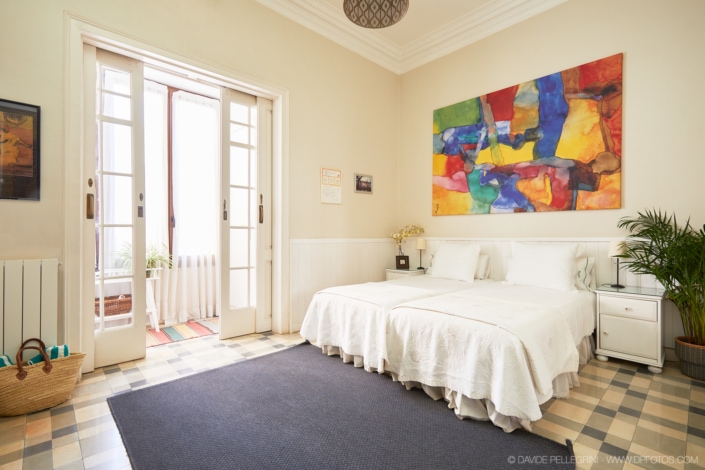 Un reportaje fotográfico de una cama en una habitación con una pintura en la pared.