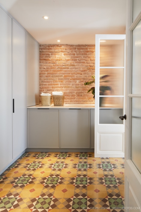 Una cocina con suelos de baldosas y pared de ladrillo, perfecta para un reportaje fotográfico de interiorismo o arquitectura.