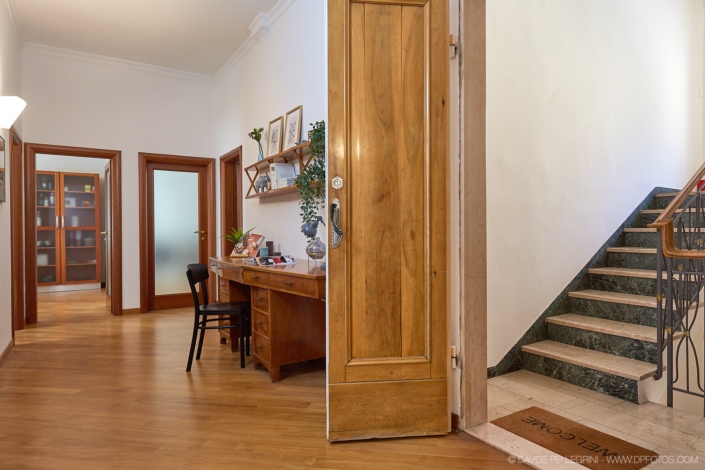 Una puerta de madera que da acceso a una habitación con escaleras y un escritorio, diseñada con un interiorismo exquisito y resaltando la belleza de la arquitectura.