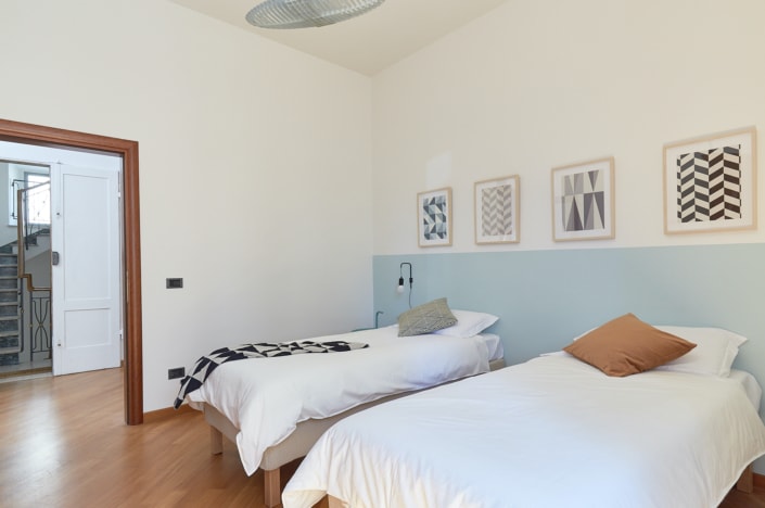 Una habitación con dos camas con un elegante diseño interior y ventilador de techo, perfecta para un reportaje de arquitectura o interiorismo.