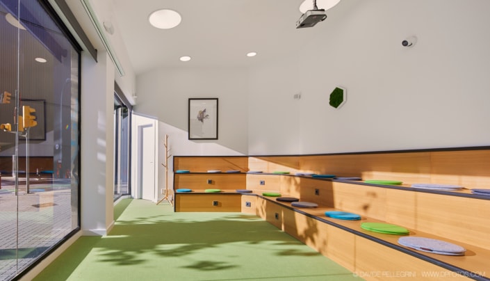 Una habitación infantil con estanterías de madera y suelo verde. El interiorismo de esta habitación está cuidadosamente diseñado con elementos arquitectónicos como estantes de madera que brindan un amplio espacio de almacenamiento para juguetes.