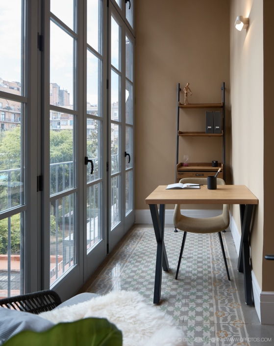 Un reportaje de interiorismo que muestra un escritorio en una habitación con grandes ventanales, destacando su arquitectura.