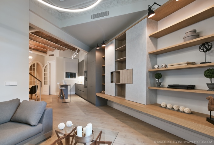 Un salón con estanterías de madera que muestra un interiorismo impecable y una arquitectura impresionante protagonizada por un suelo de madera cautivador.