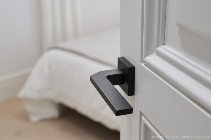 Un primer plano de una manija de puerta negra en un dormitorio interior.