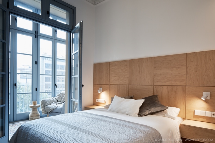 Un dormitorio con paredes de madera y una cama diseñada con un interiorismo exquisito.
