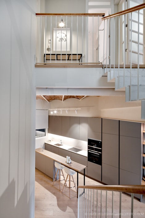 Descripción: Un reportaje de arquitectura interiorista de una cocina con una escalera que conduce a ella.