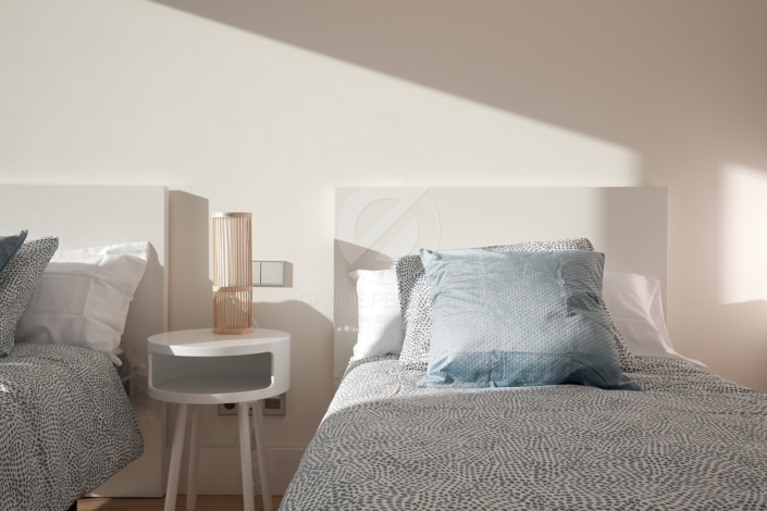 Dos camas en una habitación con paredes en un reportaje inmobiliario de alto standing.