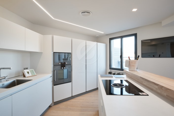 Descripción: Un elegante reportaje inmobiliario de una cocina blanca con estufa y horno de alto standing.