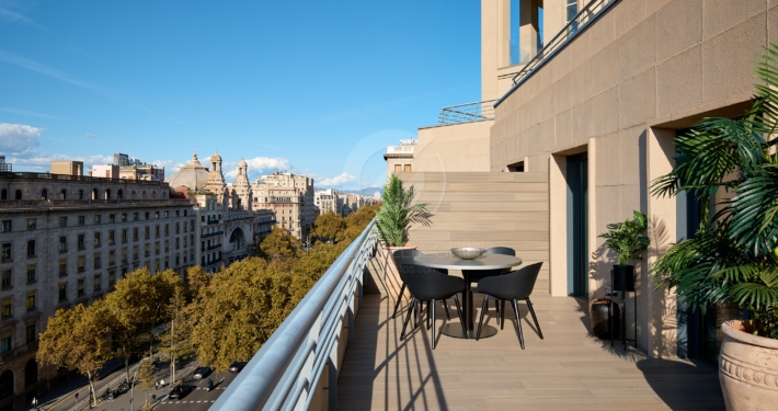 Descripción: Un balcón con una mesa y sillas, ideal para un reportaje inmobiliario de alto standing.