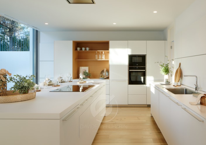 Una cocina moderna con armarios blancos y suelos de madera en una villa.