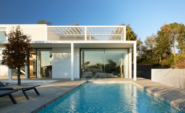 Una casa moderna que presenta impresionantes fotografías arquitectónicas de una lujosa zona de piscina con cómodos sillones.