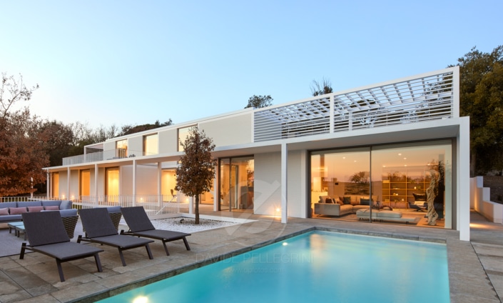 Una casa moderna con piscina y tumbonas, capturada a través de impresionantes fotografías arquitectónicas.