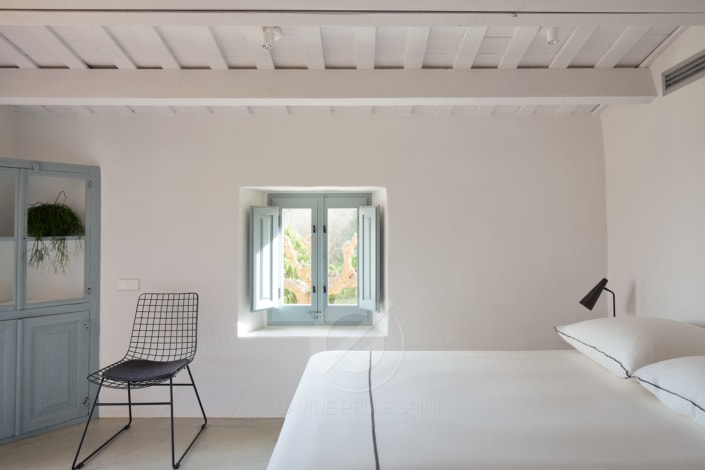 Una habitación minimalista en blanco con una cama y una silla.