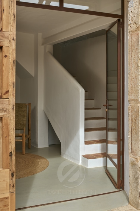 Una puerta de madera que conduce a una elegante escalera en una casa rústica.