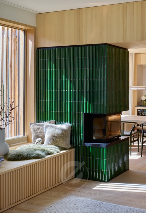 Un reportaje arquitectónico de una casa bávara que muestra una sala de estar con paredes alicatadas en verde y una chimenea.