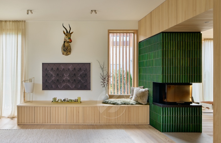 Descripción: Un reportaje fotográfico de interiores de una sala de estar con paredes verdes y una chimenea.