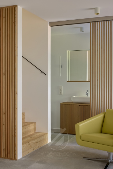 En este reportaje fotográfico de arquitectura, podrás apreciar una moderna sala de estar con paredes de madera y una silla amarilla.