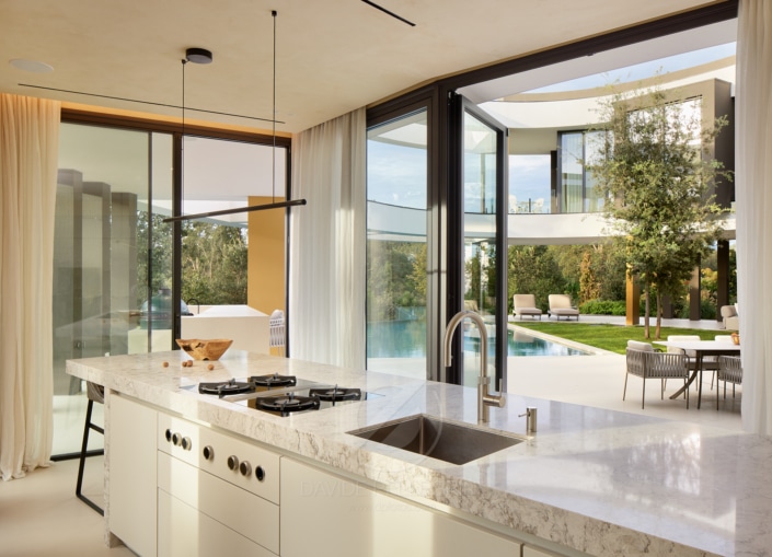 Una cocina moderna con puertas de vidrio y vista a la piscina, perfecta para una sesión de fotos inmobiliaria de alto nivel.